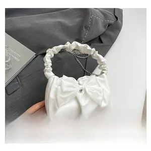 Detail of white bow handbag with pleated handle and elegant metal chain strap
