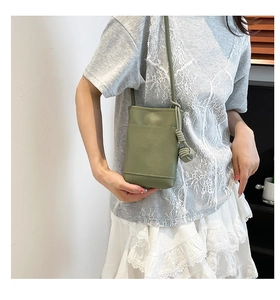 Close-up of green lychee leather phone bag featuring a stylish knotted charm detail