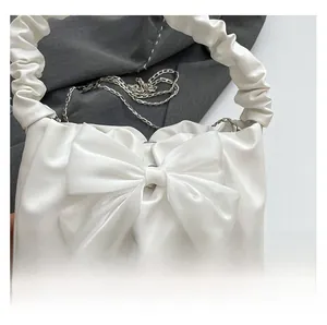 Close-up of white PU handbag with oversized mesh bow and ruffled cloud handle detail