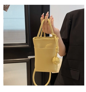 Close-up of yellow mini crossbody bag with litchi texture and stylish knot handle