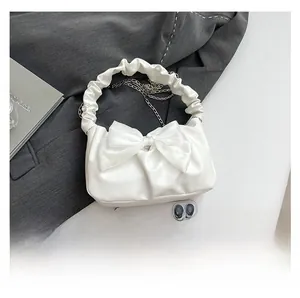 Detail of white cloud bag with large bow, ruched handle and silver metal chain strap
