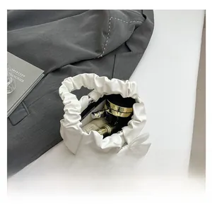Top view of white pleated cloud bag showing spacious interior with cosmetics and bow detail