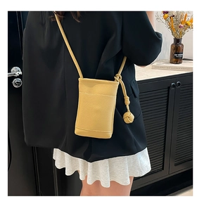 Detail view of yellow lychee pattern leather crossbody phone bag with knot decorative strap