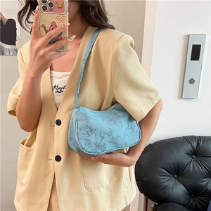 Light blue hobo bag with dark blue bamboo leaf patterns shown on a model in yellow suit