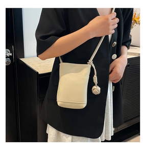 Close-up of off-white mini crossbody bag with litchi texture and decorative knot