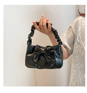 Detail of black handbag featuring a large bow and ruffled scrunchie handle for women