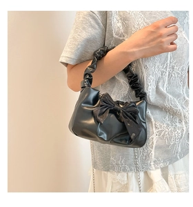 Detail of vintage black mini handbag with oversized bow and ruched handle texture