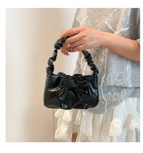Close-up of black handbag with large bow, cloud handle and delicate metal chain detail