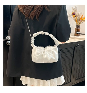 White ruched handbag with bow detail and silver chain strap shown on a black blazer