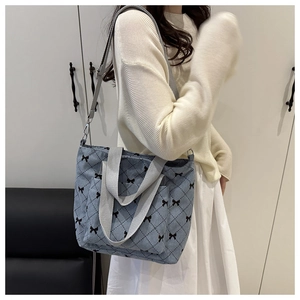 Détail du sac cabas en velours côtelé bleu avec motif nœud noir et bandoulière réglable