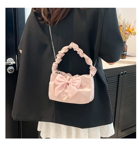 Detailed view of pink bow handbag with pleated cloud handle and metallic chain strap