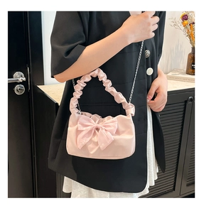 Detail of light pink handbag with large 3D bow and gathered handle and silver chain