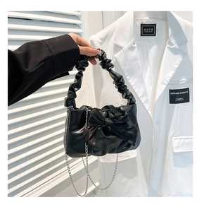 Detail of black pleated handle bag featuring mesh bow and elegant silver chain strap