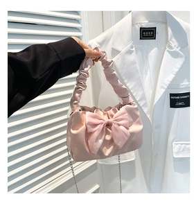 Detail of pink pleated handbag featuring a large tulle bow and elegant silver chain
