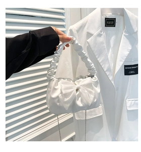 Detail of white pleated handbag with large bow and silver chain strap for women