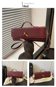Dettaglio borsa bordeaux effetto coccodrillo con chiusura a nodo dorato e tracolla