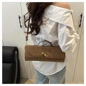 Detail view of brown crocodile texture leather bag with elegant golden knot clasp