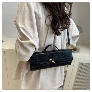 Detail view of black crocodile pattern faux leather bag with golden twist lock buckle