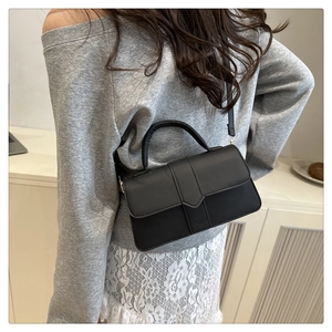 Schwarze Leder-Umhängetasche mit Klappe am Model zur Darstellung von Größe und Stil