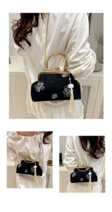 Detail of floral embroidery on black velvet evening bag with gold chain and white tassel