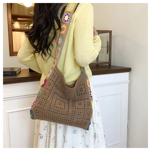 Detail of bohemian crochet tote bag featuring vibrant floral patterned wide shoulder strap