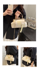 Detail of vintage floral embroidery on cream satin shell bag with metal clasp and tassel