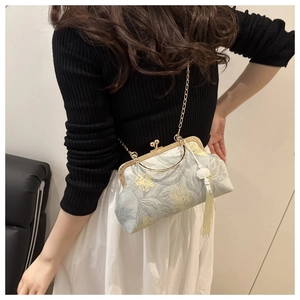 Detail of vintage jacquard chain bag with golden floral patterns and elegant cream tassel