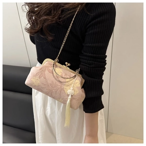 Detail of pink floral fabric clutch with gold metal frame and long fringe tassel charm