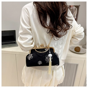 Detail view of a vintage velvet bag with white floral embroidery and a tassel charm