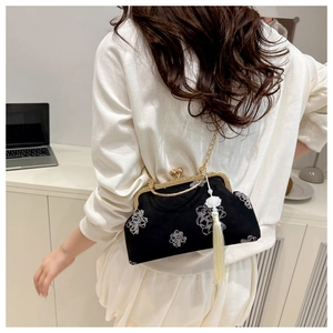 Detail of vintage black shell bag with floral embroidery and white tassel detail