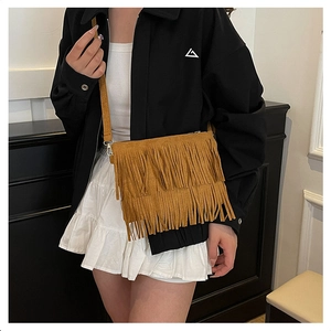 Detailed close-up of brown suede crossbody bag with long fringes and metal hook accents