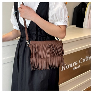 Détail d'un sac bandoulière en daim marron avec des franges bohèmes à plusieurs niveaux