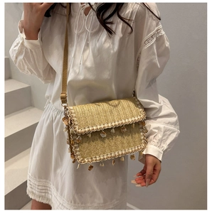 Detail of straw woven bag with white lace trim, seashell tassels, and V-pattern texture