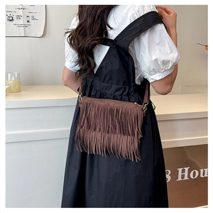Vue détaillée d'un sac bandoulière en daim marron avec des franges doubles et anneaux métal