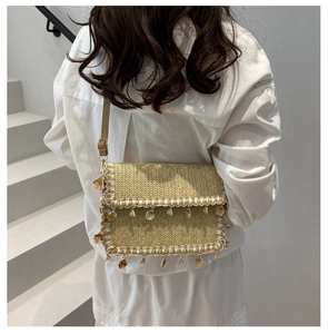Close-up of straw woven crossbody bag with decorative seashells and pearly beads detail