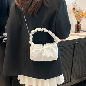 White bow chain shoulder bag with pleated handle shown on model in a soft lit setting