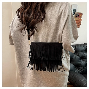 Detailed close-up of a black fringe crossbody bag in soft suede texture with gold zipper