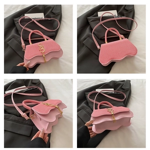 Detail of pink fashion handbag featuring golden SS logo, long tassels and woven texture flap