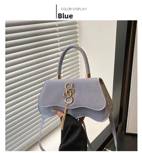 Close-up of blue textured fabric bag featuring golden tassel and wave-edge flap
