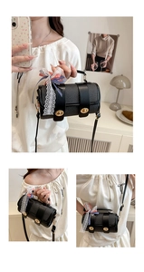 Detail of woven black cylinder bag with lace trim, plaid bow, and golden turn-lock