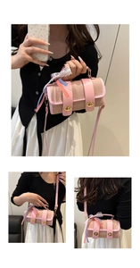 Detail of pink woven crossbody bag showing dual gold locks and decorative lace ribbons