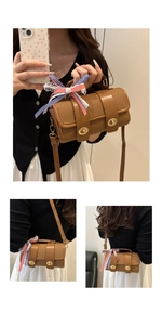 Detail of a brown cylindrical woven bag featuring gold twist locks and a decorative ribbon