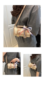 Detail of woven straw bucket bag featuring leather trim, gold twist locks and ribbon bow