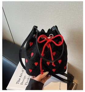 Detail of red heart embroidery and woven drawstring on black bucket bag surface