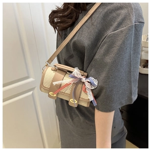Détail du sac bandoulière tressé cylindrique avec garniture en cuir et nœud décoratif