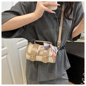 Détail du sac polochon tissé beige avec garniture en cuir et ruban à carreaux