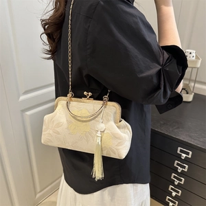 Floral jacquard handbag with gold chain strap and elegant tassel accessory shown on model