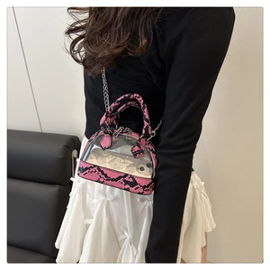 Pink snake-print trim transparent shell bag with metal chain shown on model in studio