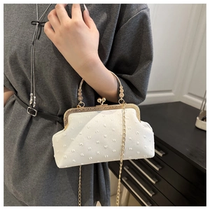 Detailed view of the vintage white shell bag with embossed texture and gold metal clasp