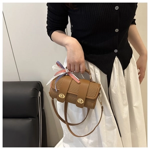 Détail d'un sac cylindrique marron texturé avec lanière en cuir et fermoir doré